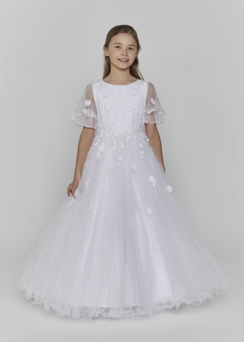A girl in a white communion dress with sheer floral sleeves and a full tulle skirt