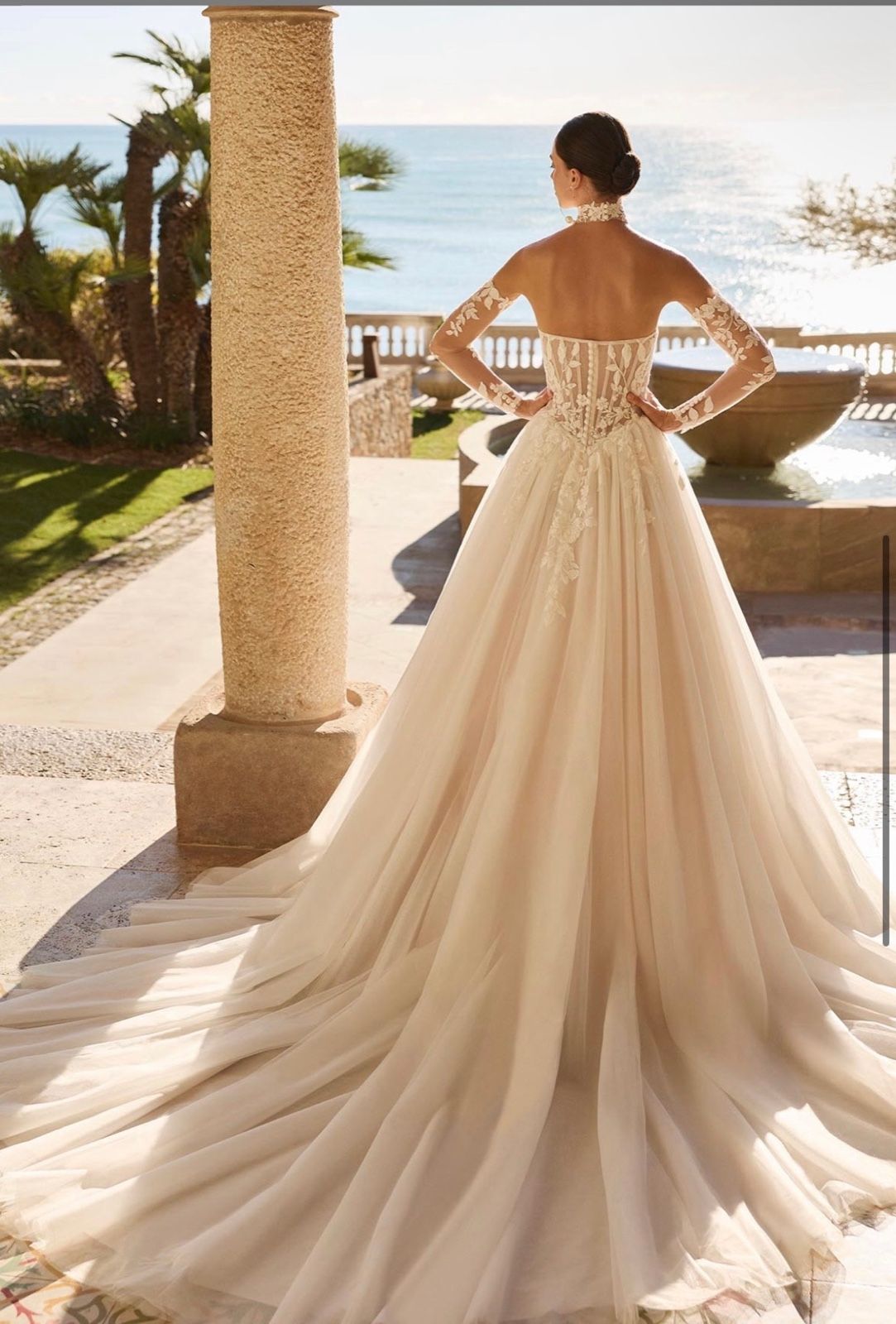 The long tulle train of a champagne ballgown with lace sleeves