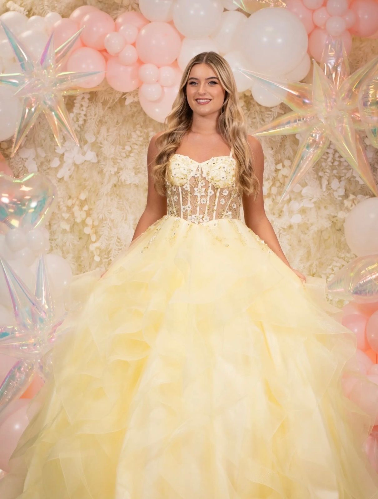 A pale yellow prom gown with a lace corset bodice and full ruffled skirt